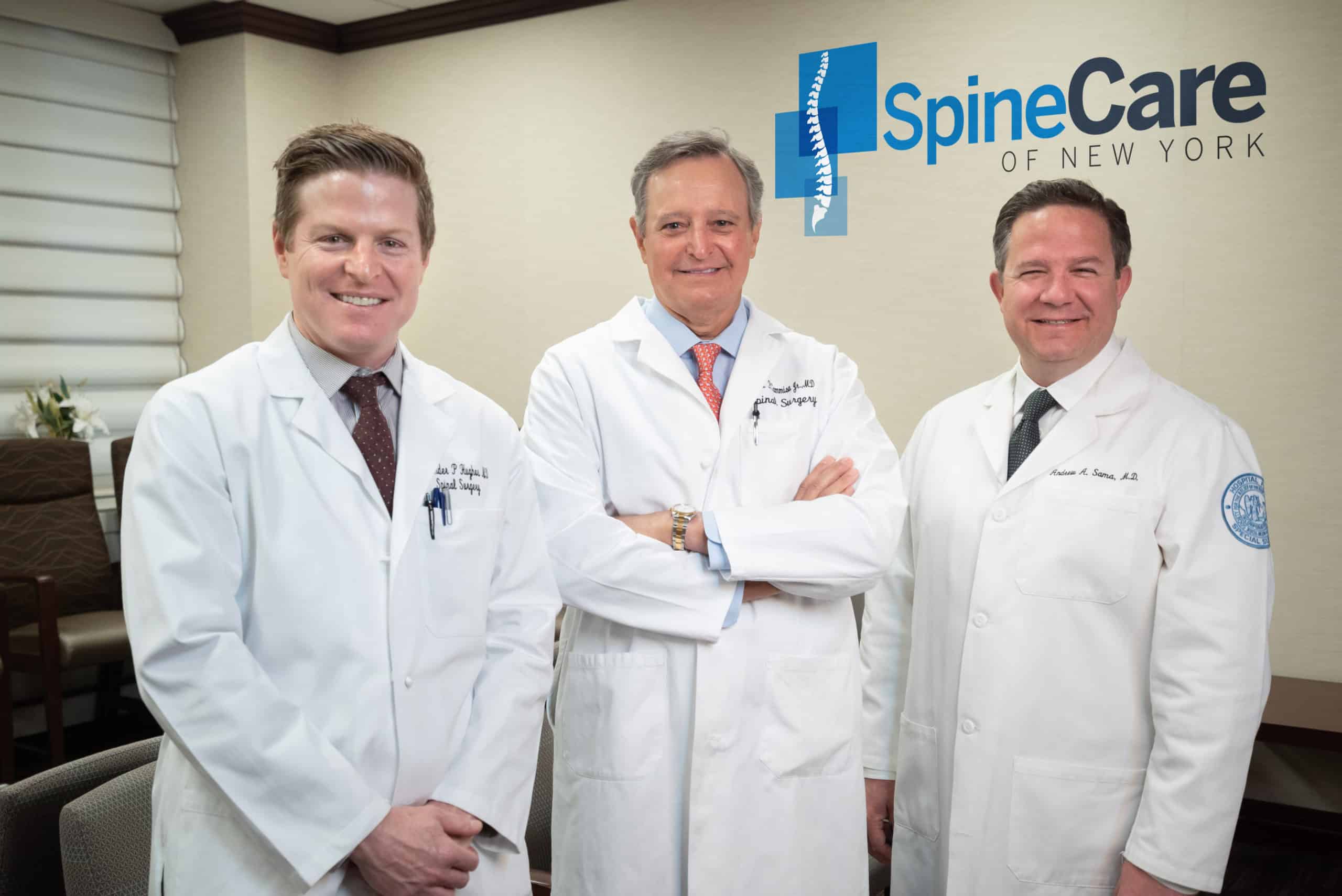Drs. Hughes, Cammisa, and Sama - Orthopedic Surgeons at SpineCare of NY - in office with logo behind them